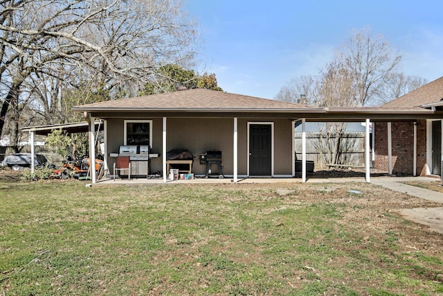 back of property with a lawn, roof with shingles, and fence