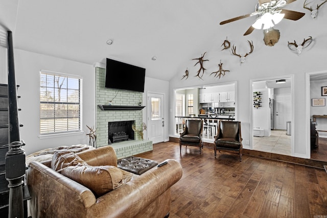 living area with baseboards, a fireplace, high vaulted ceiling, a ceiling fan, and wood-type flooring