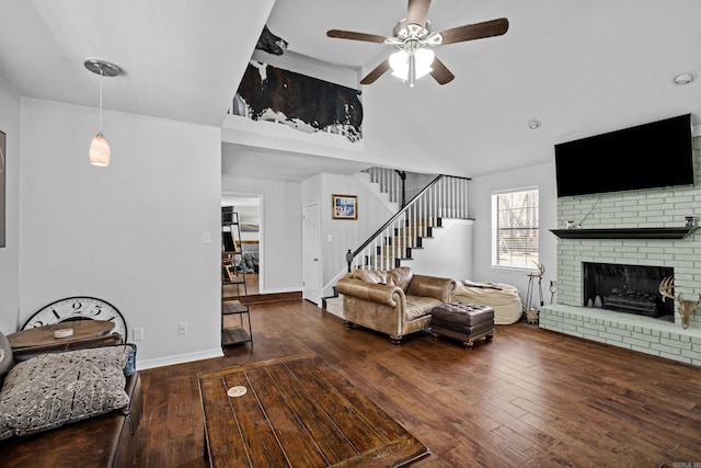 living area featuring stairs, hardwood / wood-style flooring, a brick fireplace, and ceiling fan