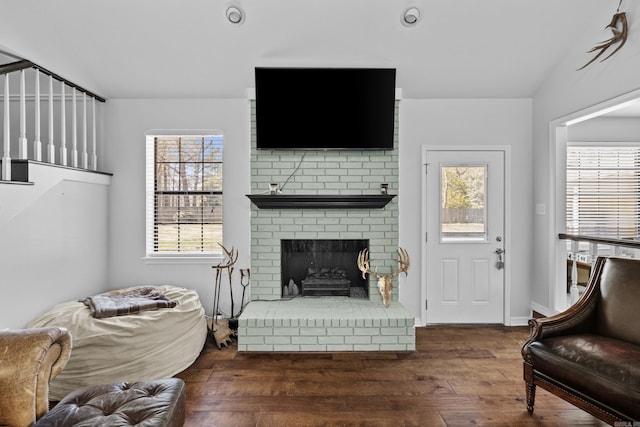 living area with lofted ceiling, a brick fireplace, and wood finished floors