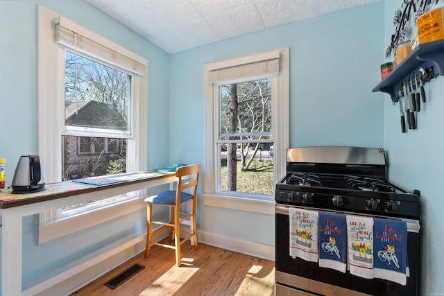 interior space featuring visible vents, gas range, baseboards, and wood finished floors