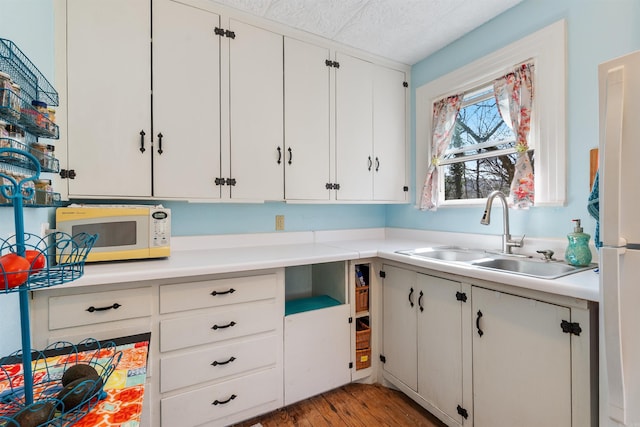 kitchen featuring a sink, white appliances, white cabinets, and light countertops