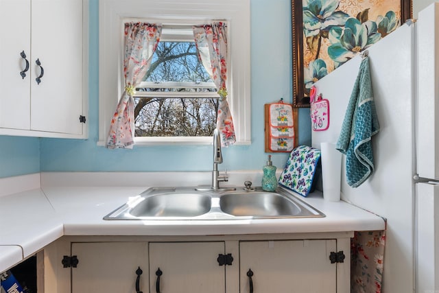 kitchen with white cabinetry, light countertops, and a sink