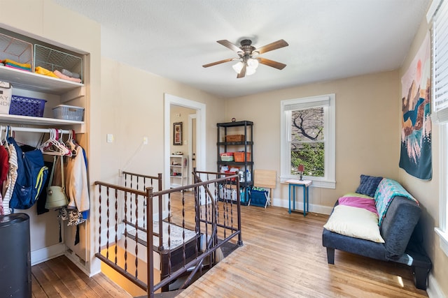 interior space featuring baseboards, a textured ceiling, a ceiling fan, and hardwood / wood-style flooring