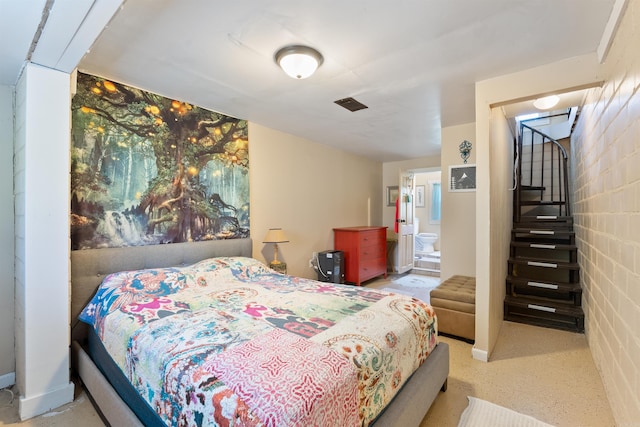 bedroom featuring concrete block wall and visible vents