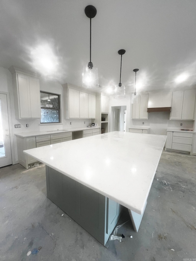 kitchen with a spacious island, pendant lighting, white cabinets, and unfinished concrete floors