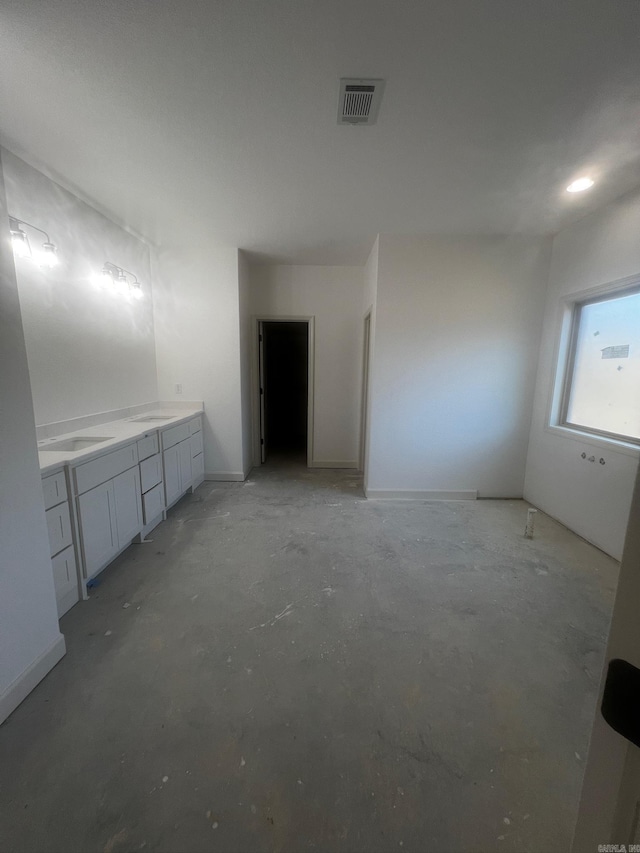 interior space with double vanity, unfinished concrete floors, visible vents, and a sink