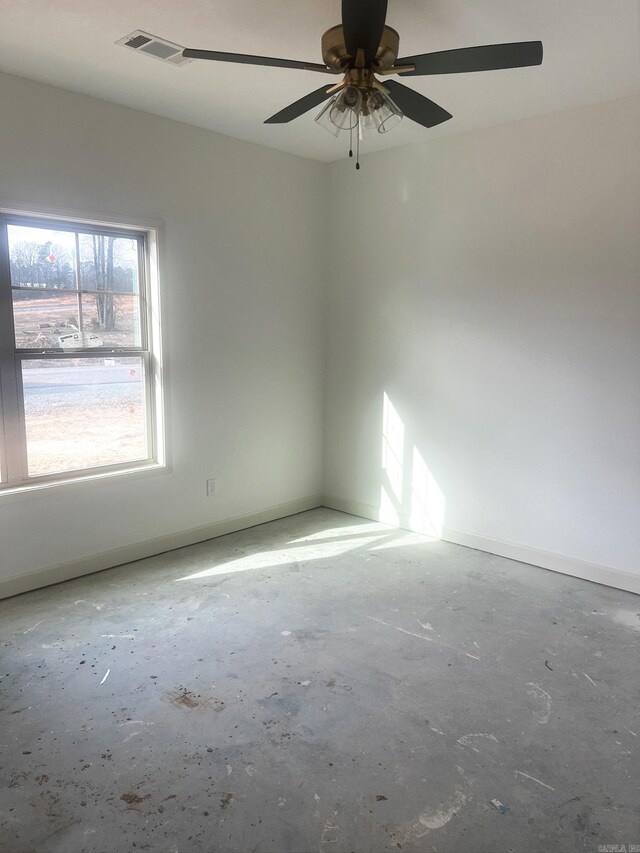 unfurnished room featuring visible vents, unfinished concrete flooring, baseboards, and a ceiling fan