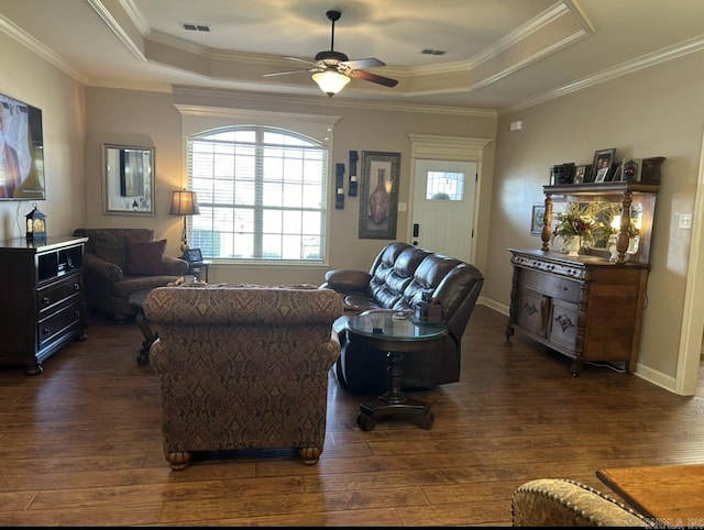 living area featuring visible vents, a raised ceiling, dark wood finished floors, and a ceiling fan