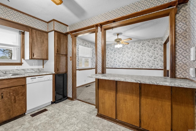 kitchen with wallpapered walls, visible vents, white dishwasher, and a textured ceiling