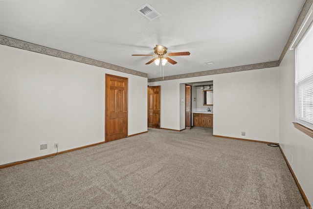 unfurnished bedroom featuring visible vents, baseboards, ensuite bath, ceiling fan, and light colored carpet