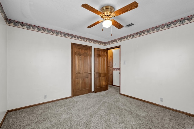 unfurnished bedroom featuring a ceiling fan, light colored carpet, visible vents, and baseboards