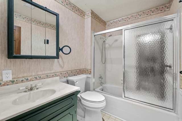 full bathroom featuring wallpapered walls, bath / shower combo with glass door, toilet, vanity, and a textured ceiling