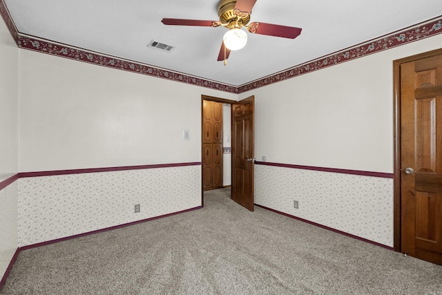 unfurnished room with a ceiling fan, visible vents, baseboards, wallpapered walls, and carpet flooring