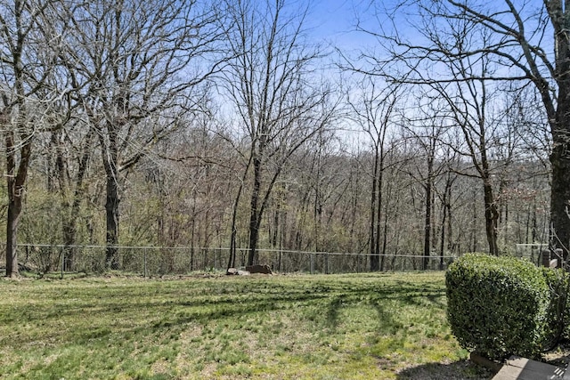 view of yard with a wooded view and fence