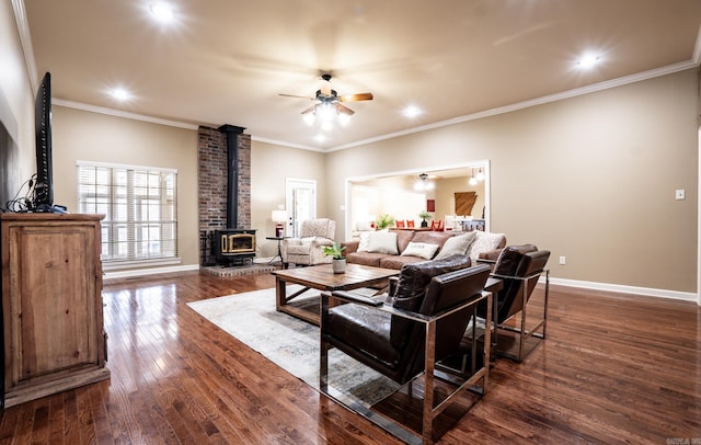 living room with dark wood-style floors, baseboards, a wood stove, ceiling fan, and crown molding