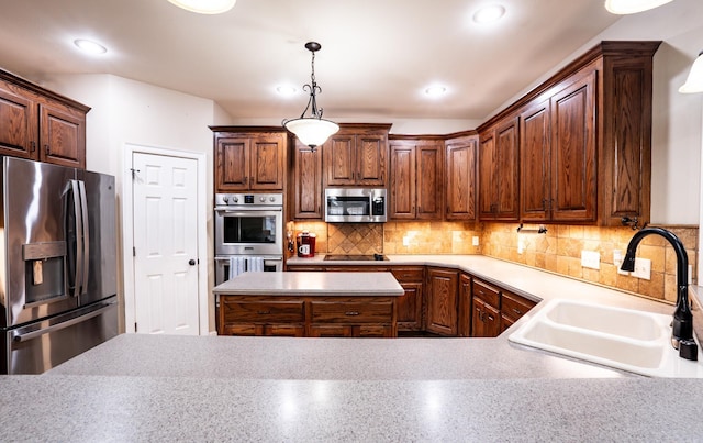 kitchen featuring a sink, decorative light fixtures, tasteful backsplash, stainless steel appliances, and light countertops