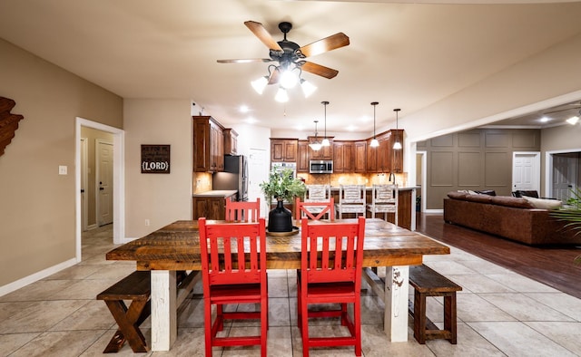 dining space with light tile patterned flooring, a ceiling fan, and baseboards