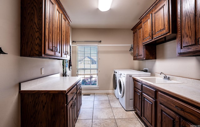 laundry room with light tile patterned floors, baseboards, cabinet space, a sink, and independent washer and dryer