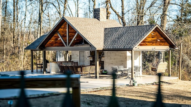 exterior space with roof with shingles and a chimney