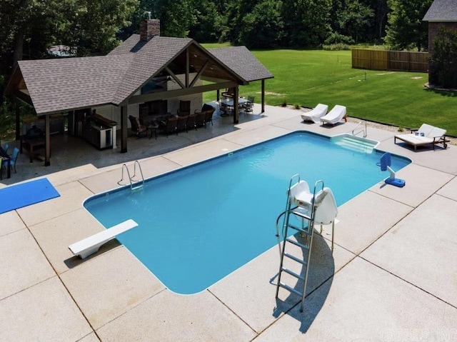 view of pool featuring a water slide, fence, a yard, a patio, and a diving board