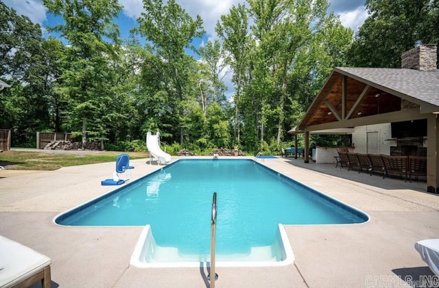 pool with a patio and a water slide