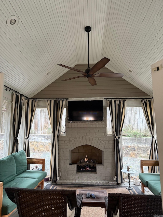 living room with lofted ceiling, plenty of natural light, a ceiling fan, and an outdoor brick fireplace