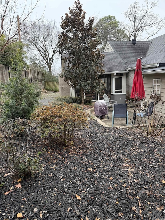 rear view of property with a patio, brick siding, roof with shingles, and fence