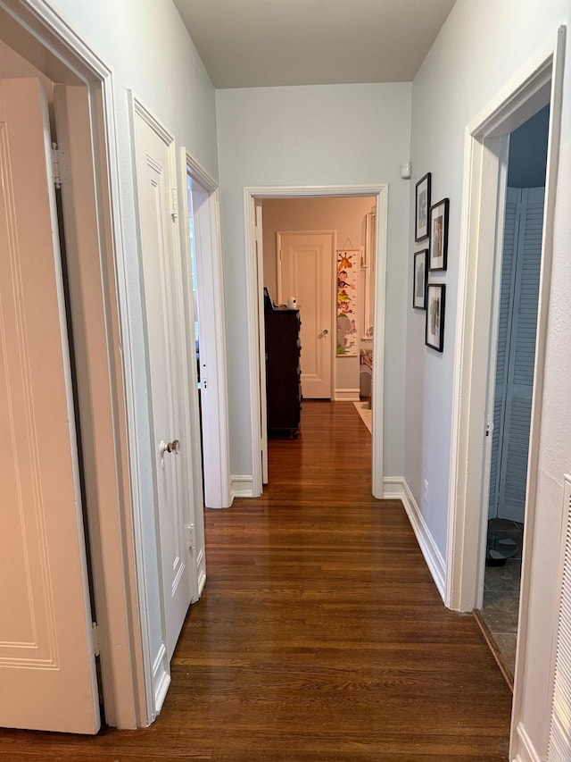 hallway featuring dark wood finished floors and baseboards