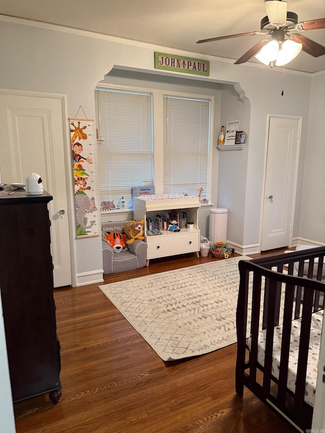 bedroom featuring baseboards, a ceiling fan, dark wood finished floors, and crown molding