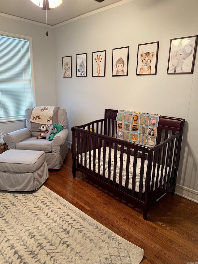 bedroom featuring crown molding, a nursery area, and wood finished floors