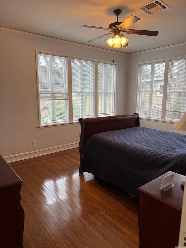 bedroom featuring visible vents, a ceiling fan, dark wood-style floors, crown molding, and baseboards