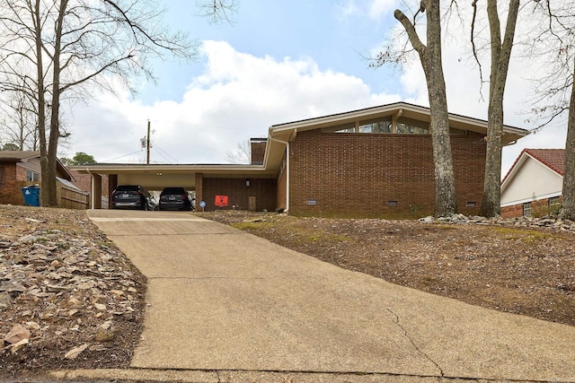 view of front of property with a carport, crawl space, concrete driveway, and brick siding