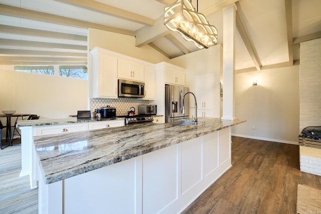 kitchen with lofted ceiling with beams, a sink, stainless steel appliances, decorative backsplash, and dark wood-style flooring