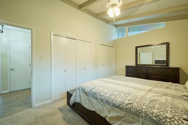 carpeted bedroom with lofted ceiling with beams and two closets