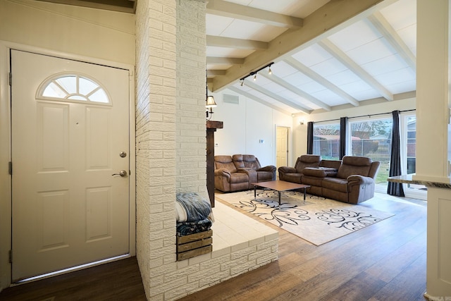 living area featuring vaulted ceiling with beams, visible vents, dark wood-style flooring, and ornate columns