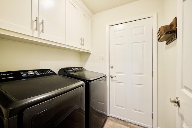 laundry area featuring cabinet space, separate washer and dryer, and light wood-style floors