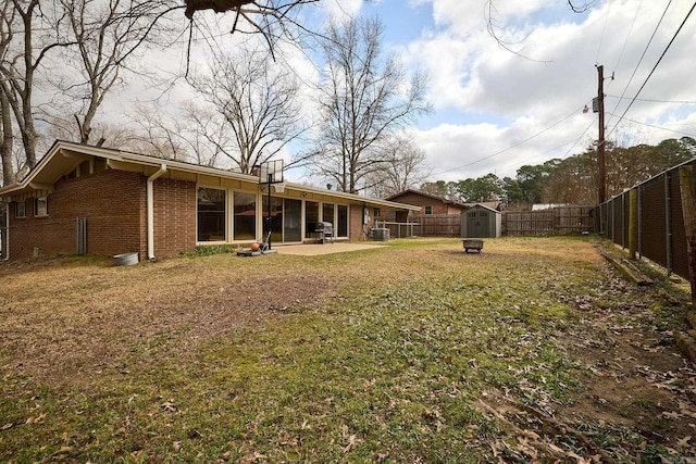 view of yard featuring a patio area, an outbuilding, a fenced backyard, and a shed