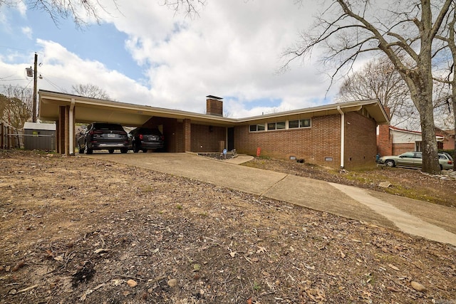 view of front facade with an attached carport, driveway, a chimney, crawl space, and brick siding