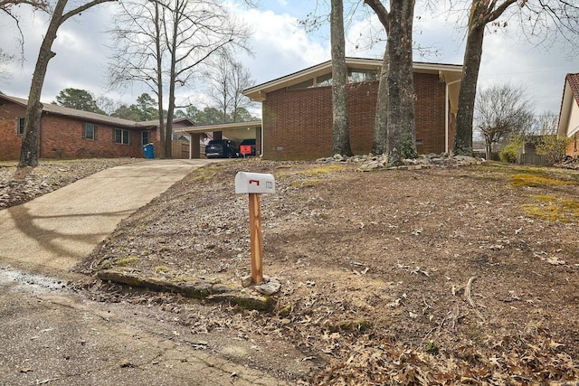 exterior space featuring brick siding, driveway, and a carport