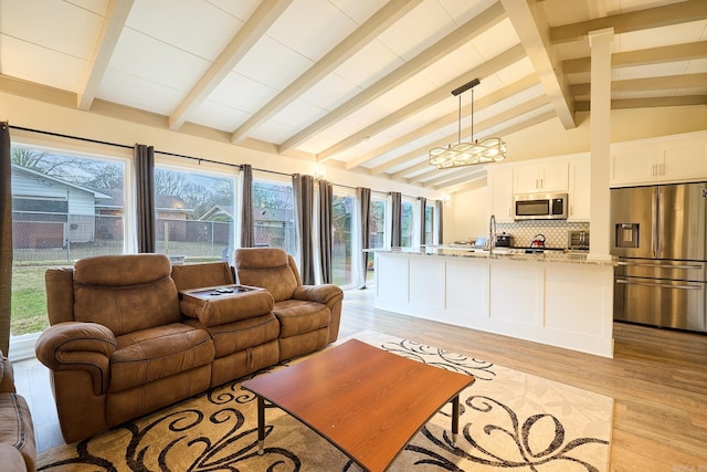 living area with lofted ceiling with beams and light wood-style floors