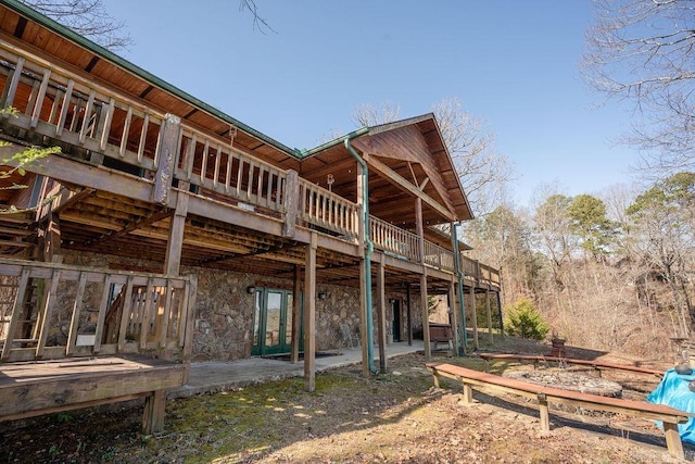 rear view of house featuring stone siding and a wooden deck