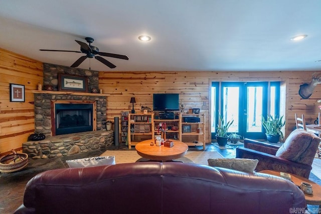 living room with recessed lighting, wooden walls, ceiling fan, and a fireplace