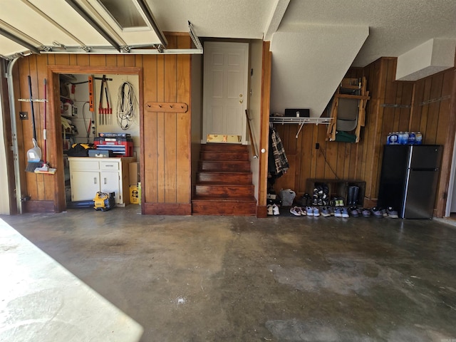 garage with wood walls and freestanding refrigerator