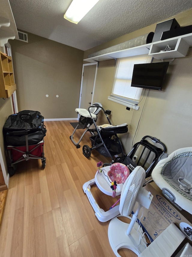 exercise room with visible vents, baseboards, a textured ceiling, and wood finished floors