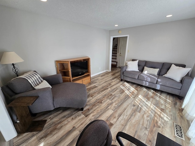 living area featuring wood finished floors, visible vents, baseboards, recessed lighting, and a textured ceiling