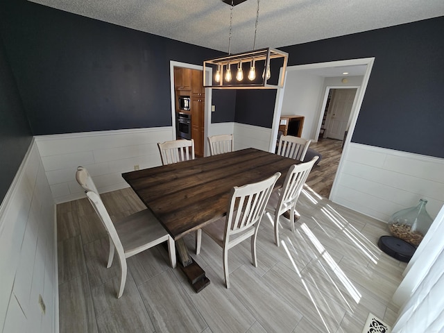 dining room with a wainscoted wall and a textured ceiling