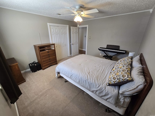 carpeted bedroom with visible vents, ceiling fan, ornamental molding, a closet, and a textured ceiling