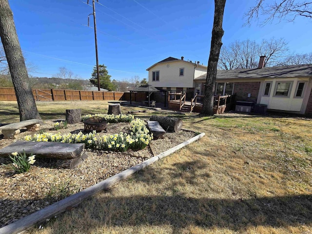 view of yard featuring a wooden deck, fence, and an outdoor fire pit