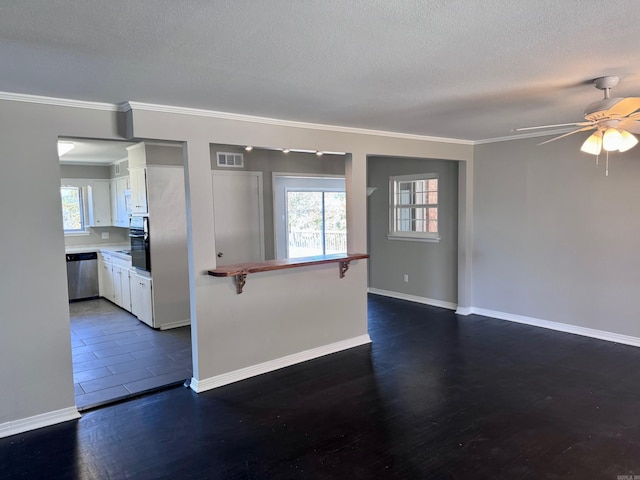 empty room with visible vents, dark wood-type flooring, baseboards, ceiling fan, and a textured ceiling